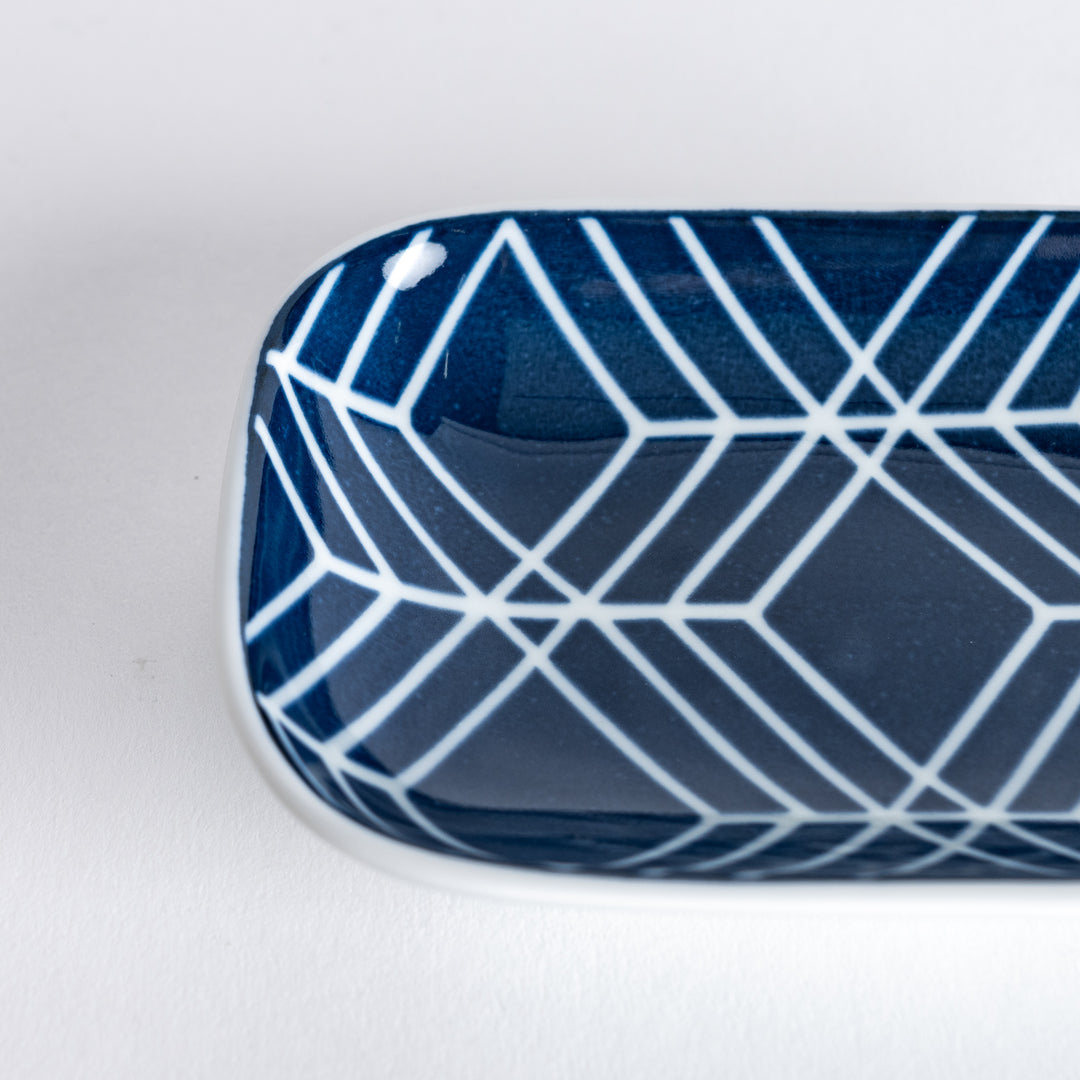 Close-up of the geometric pattern on the sauce dish, featuring a bold navy blue design on a white surface.