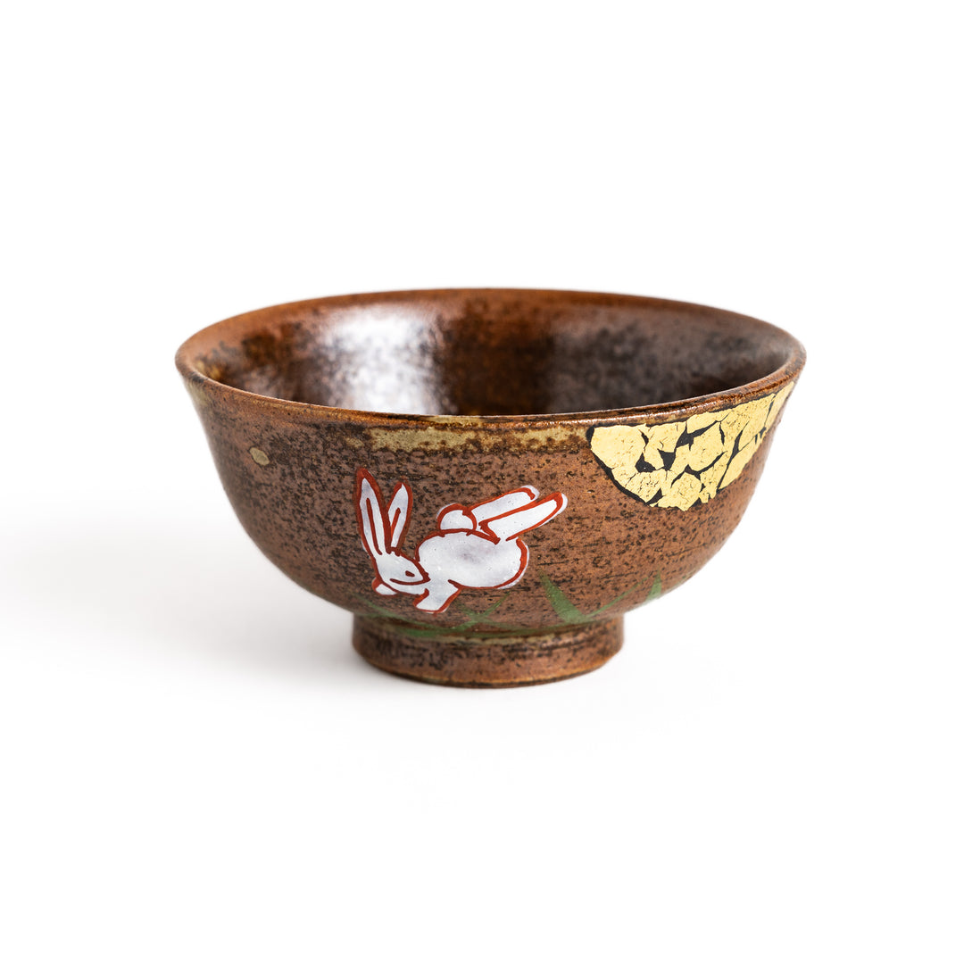 Brown ceramic sake cup with a playful rabbit design and a unique crackled glaze, perfect for enjoying a traditional cup of sake.