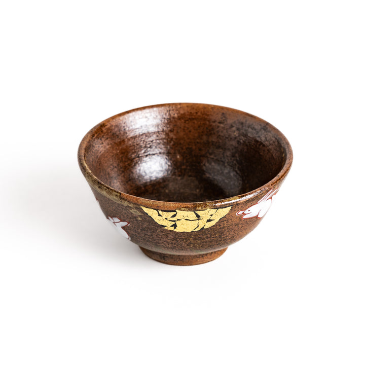 Brown ceramic sake cup with a playful rabbit design and a unique crackled glaze, perfect for enjoying a traditional cup of sake.