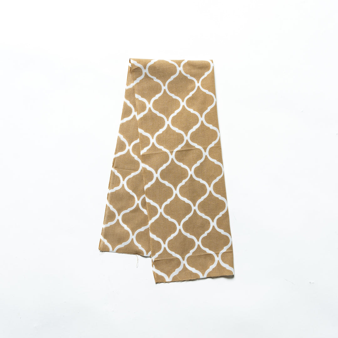 Beige hand towel with a Moroccan tile-inspired white lattice pattern, folded neatly.