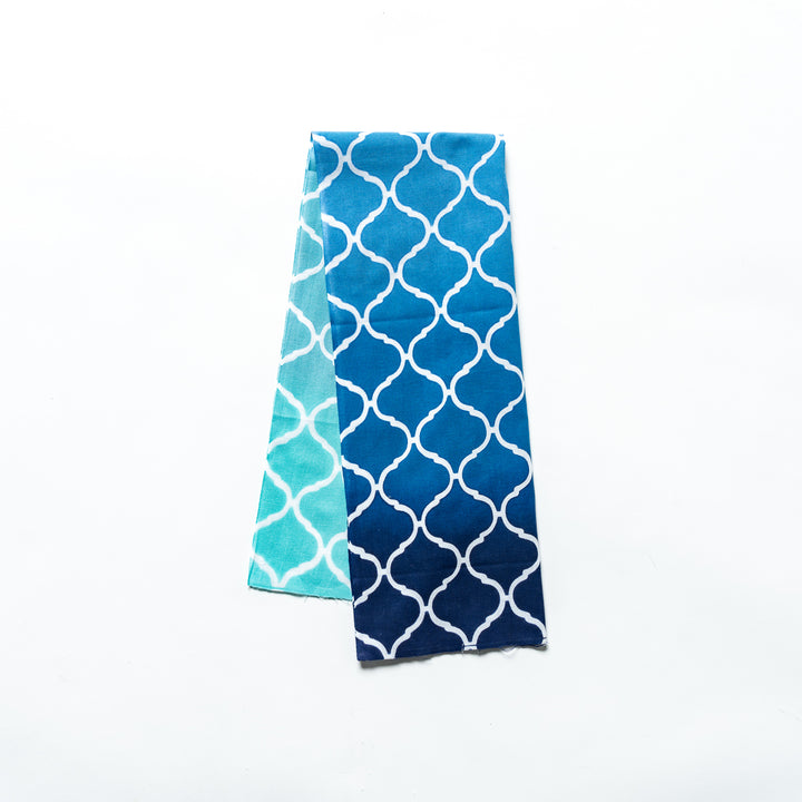 Blue hand towel with a Moroccan tile-inspired white lattice pattern, folded neatly.