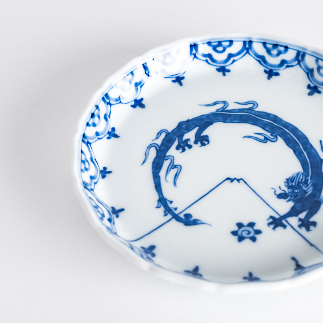 A small round ceramic plate with a blue dragon and Mount Fuji design, bordered with intricate patterns.