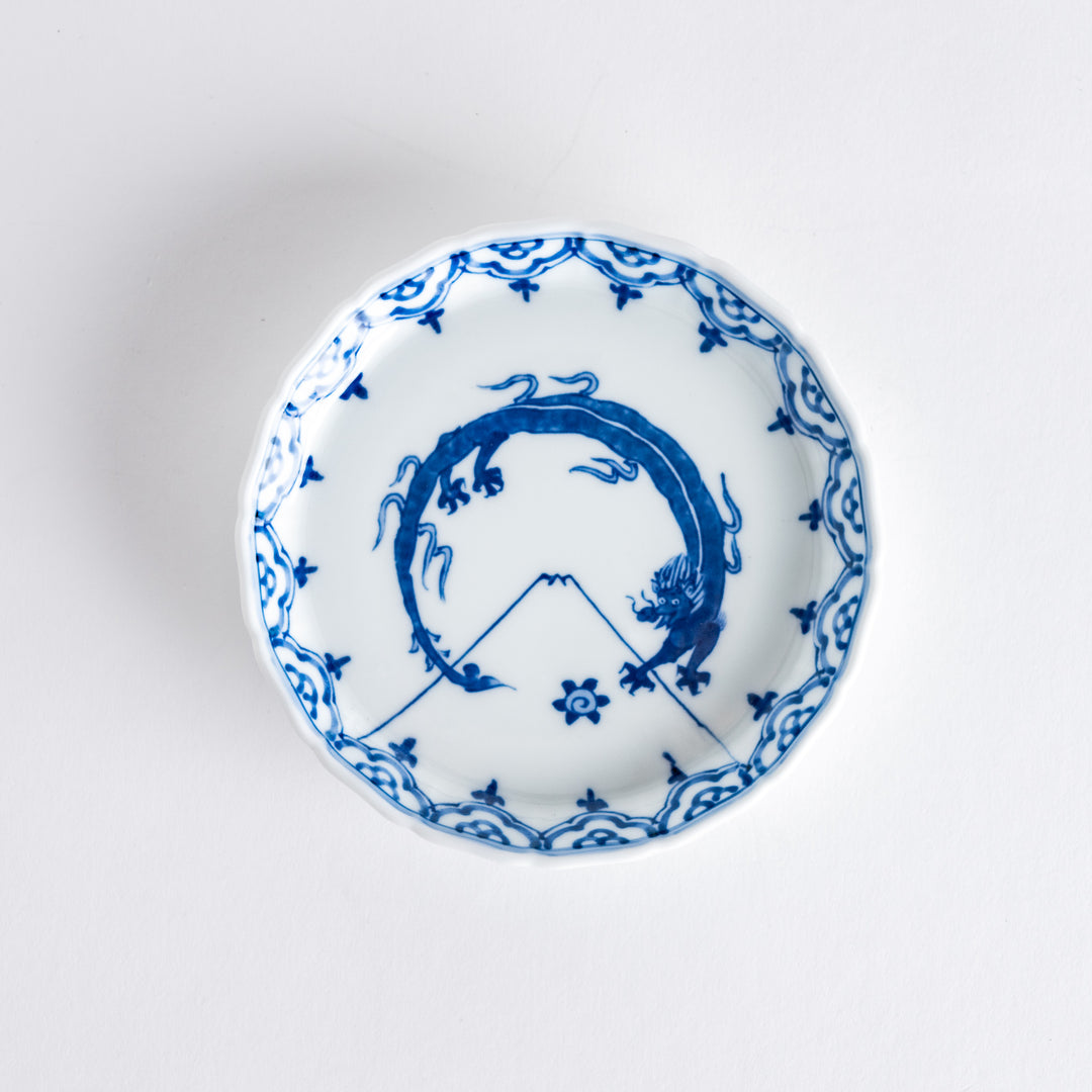 A small round ceramic plate with a blue dragon and Mount Fuji design, bordered with intricate patterns.