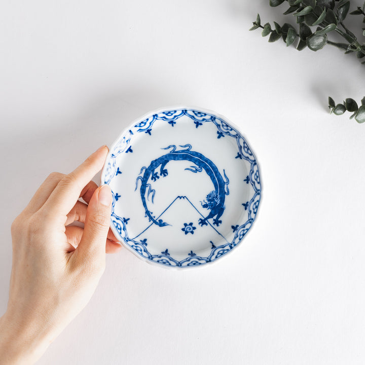 A small round ceramic plate with a blue dragon and Mount Fuji design, bordered with intricate patterns.