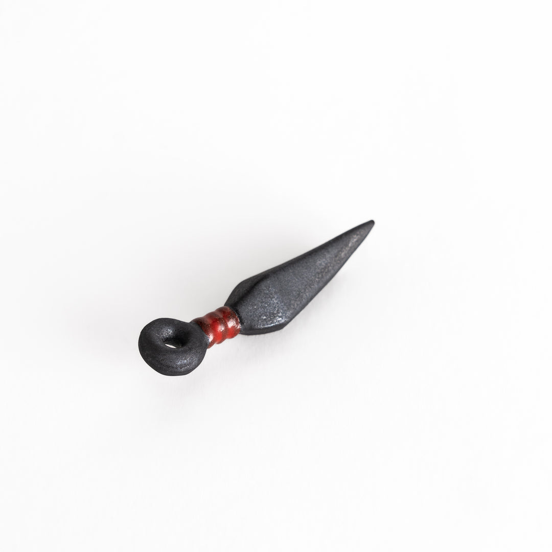 A slightly angled view of the kunai-shaped chopstick rest, emphasizing its sharp triangular shape and textured surface.