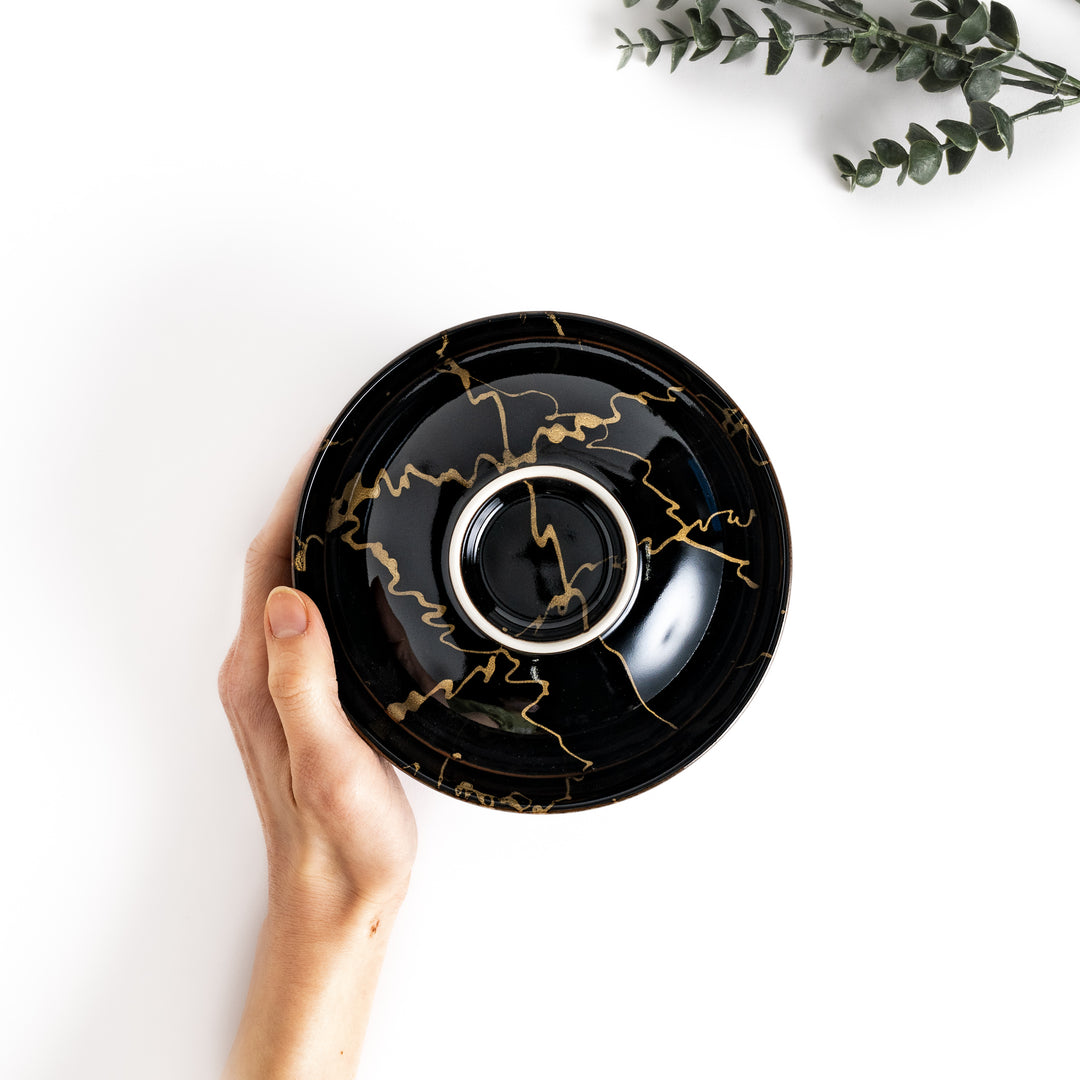 Hand holding a black ceramic donburi bowl with a striking gold marbled design, perfect for serving delicious and stylish Japanese rice dishes.