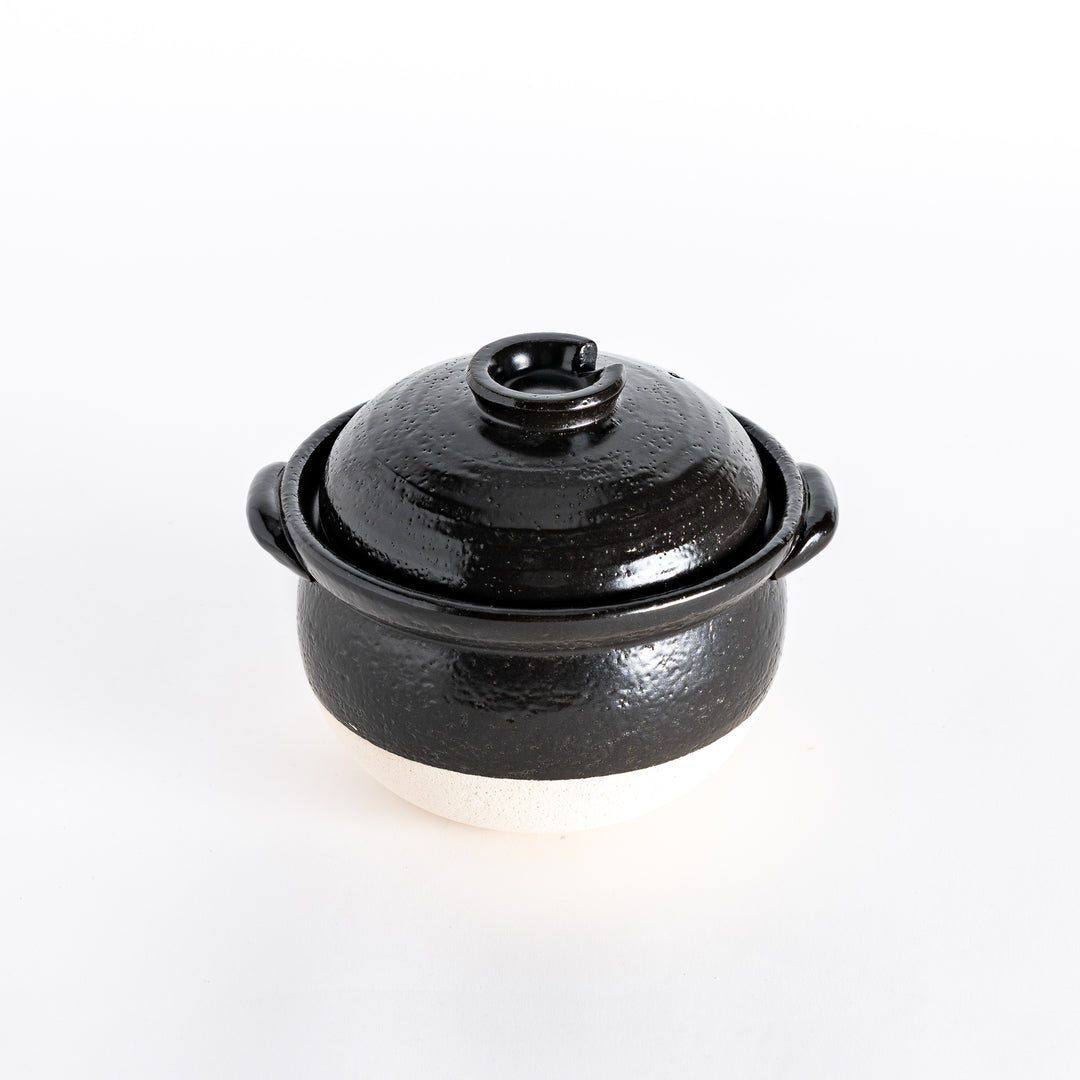 Donabe with a glossy black lid and black textured body, resting on a white base.