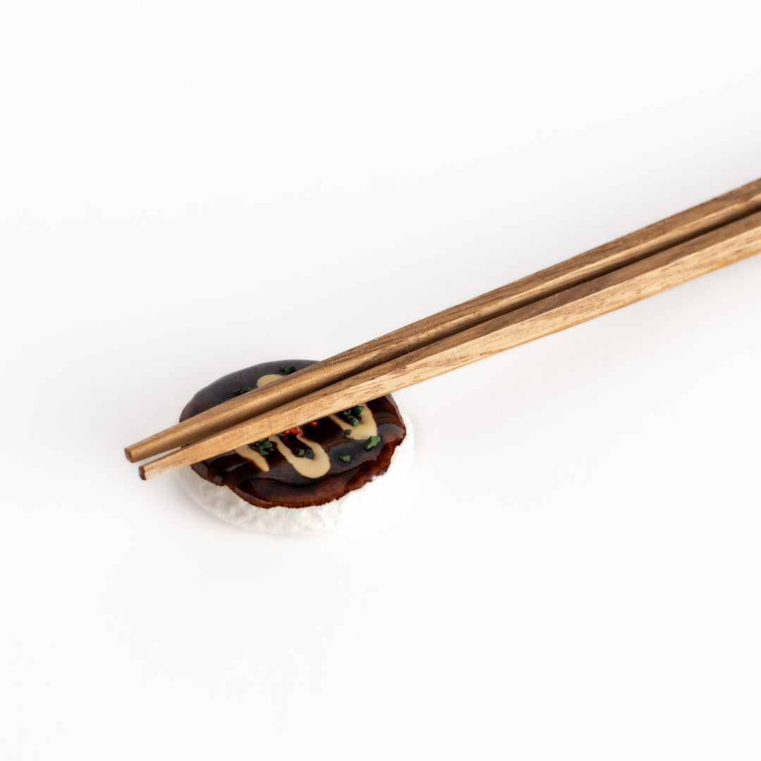 Close-up view of the okonomiyaki-shaped chopstick rest with chopsticks, emphasizing its intricate details and realistic toppings.