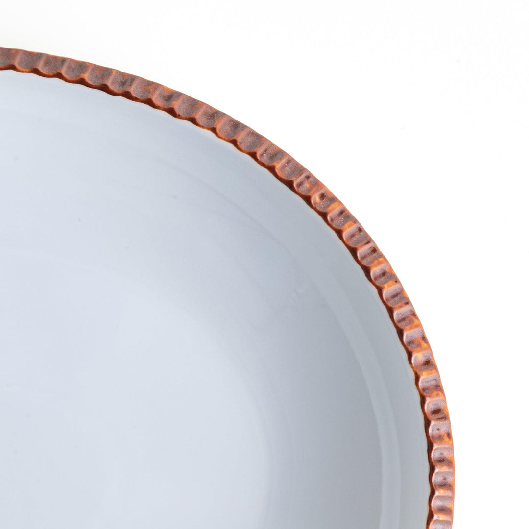 An oval-shaped white dinner plate with a rustic scallop-edged design. The border comes in blue, brown, and olive.