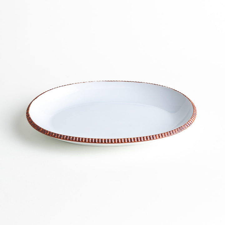 An oval-shaped white dinner plate with a rustic scallop-edged design. The border comes in blue, brown, and olive.