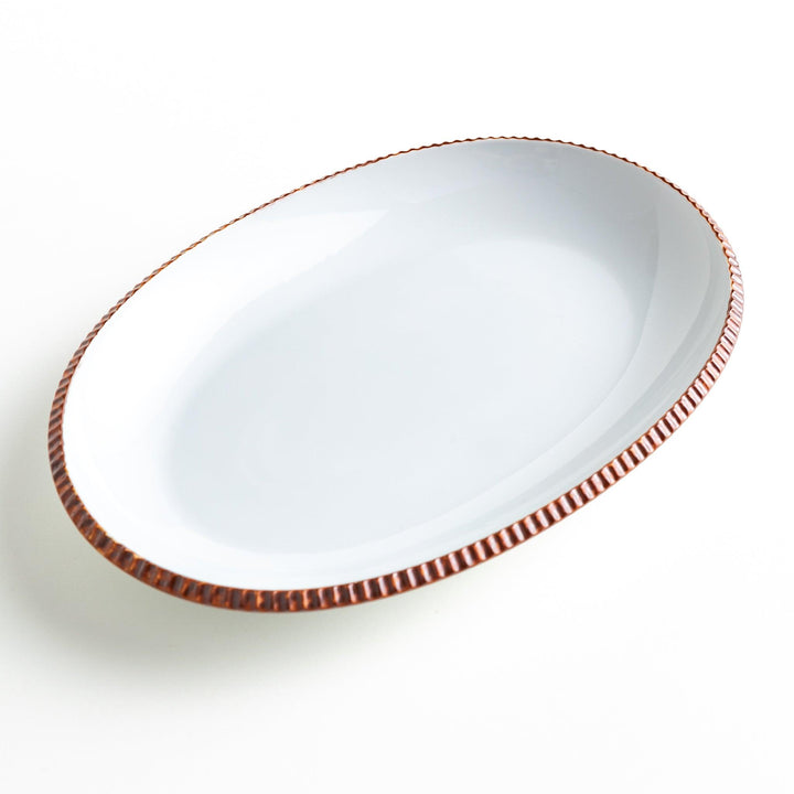 An oval-shaped white dinner plate with a rustic scallop-edged design. The border comes in blue, brown, and olive.