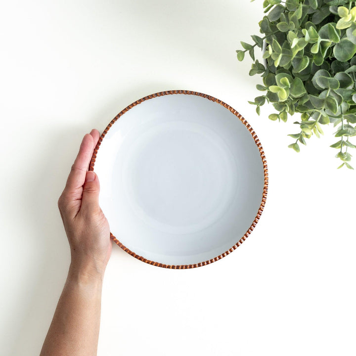 A round white dinner plate with a rustic scallop-edged border. The border comes in blue, brown, and olive.