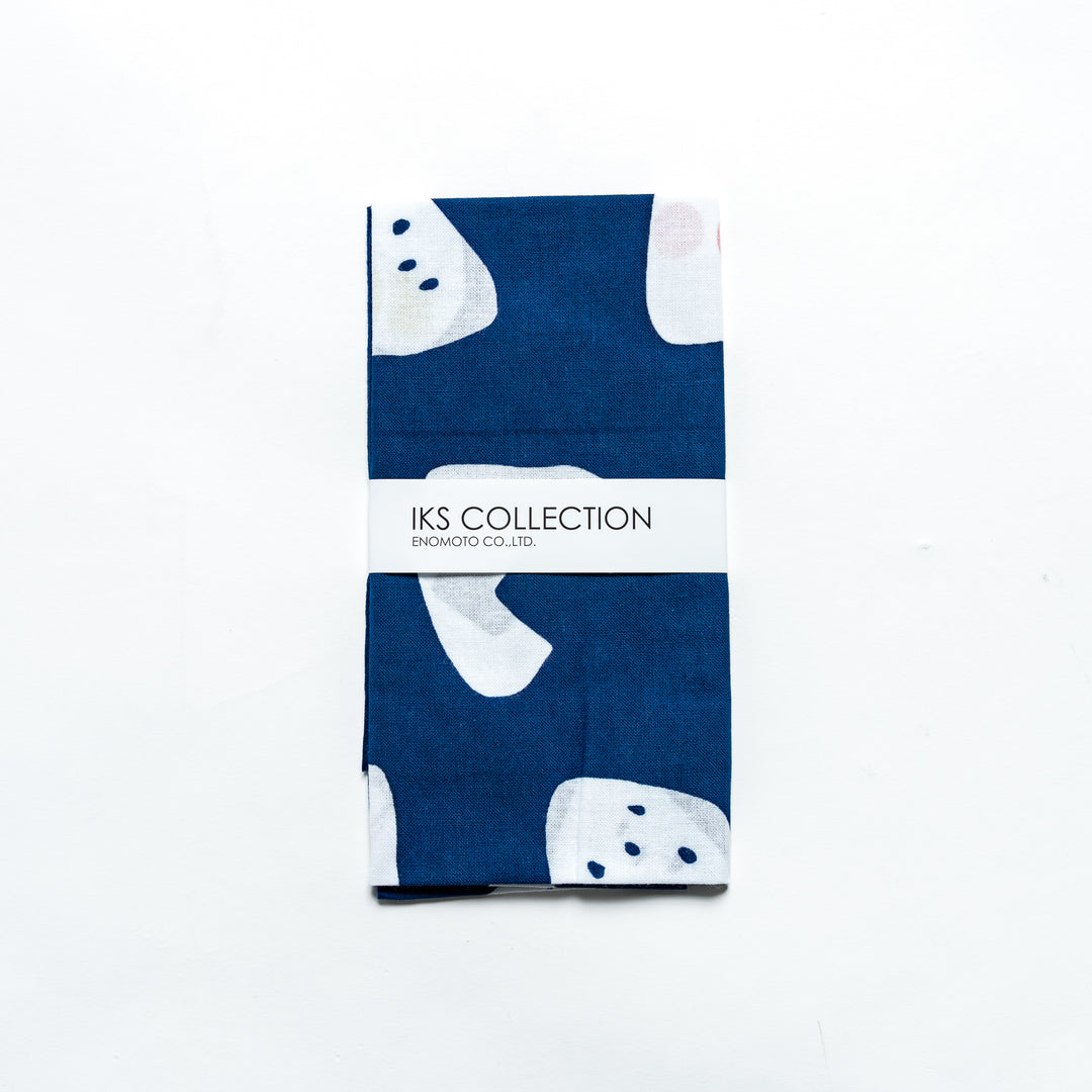 Navy tenugui neatly folded with product sleeve, featuring playful rice ball patterns.