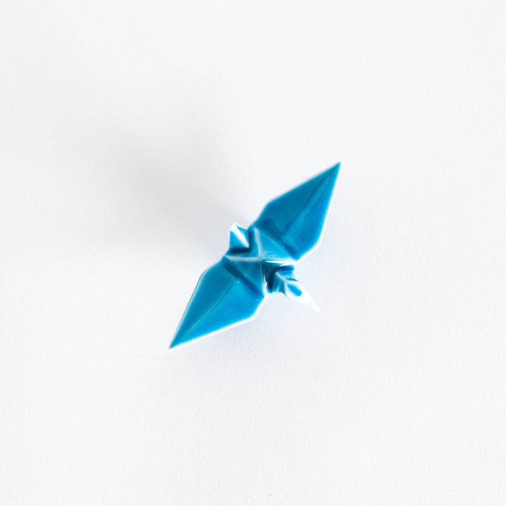 Top view of the light blue ceramic crane-shaped chopstick rest on a white surface.