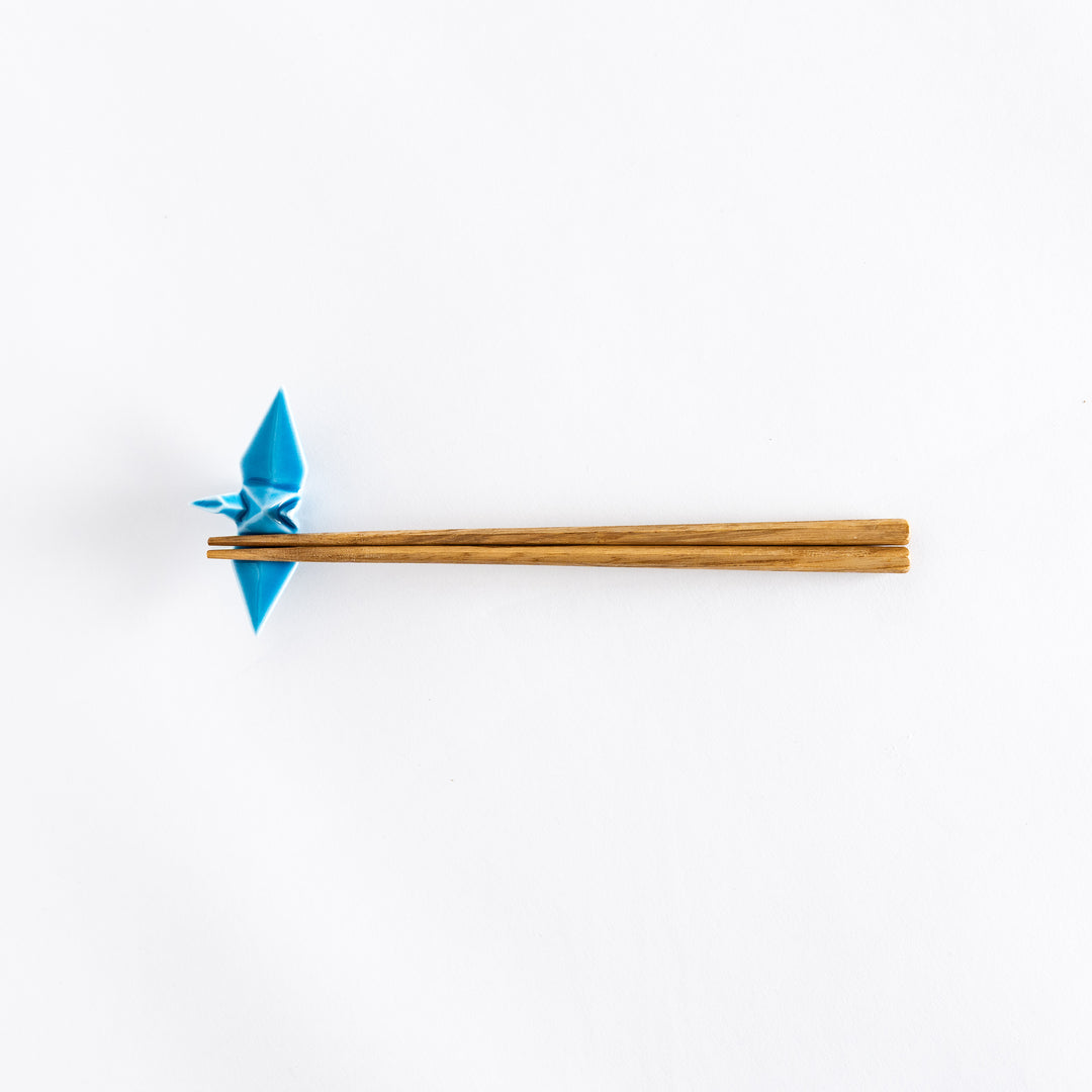 Wide view of chopsticks resting on the light blue ceramic crane-shaped chopstick rest.