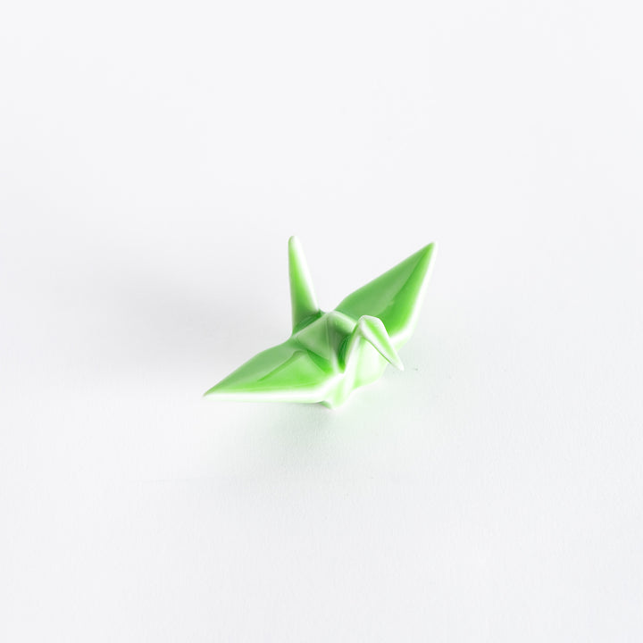 A green ceramic crane-shaped chopstick rest on a white background.