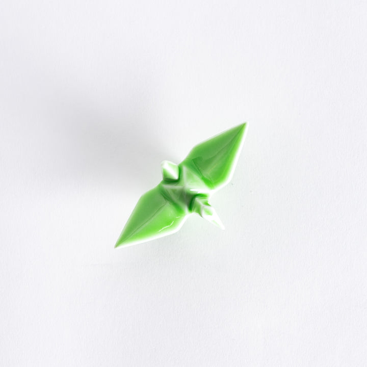 Top view of the green ceramic crane-shaped chopstick rest on a white surface.