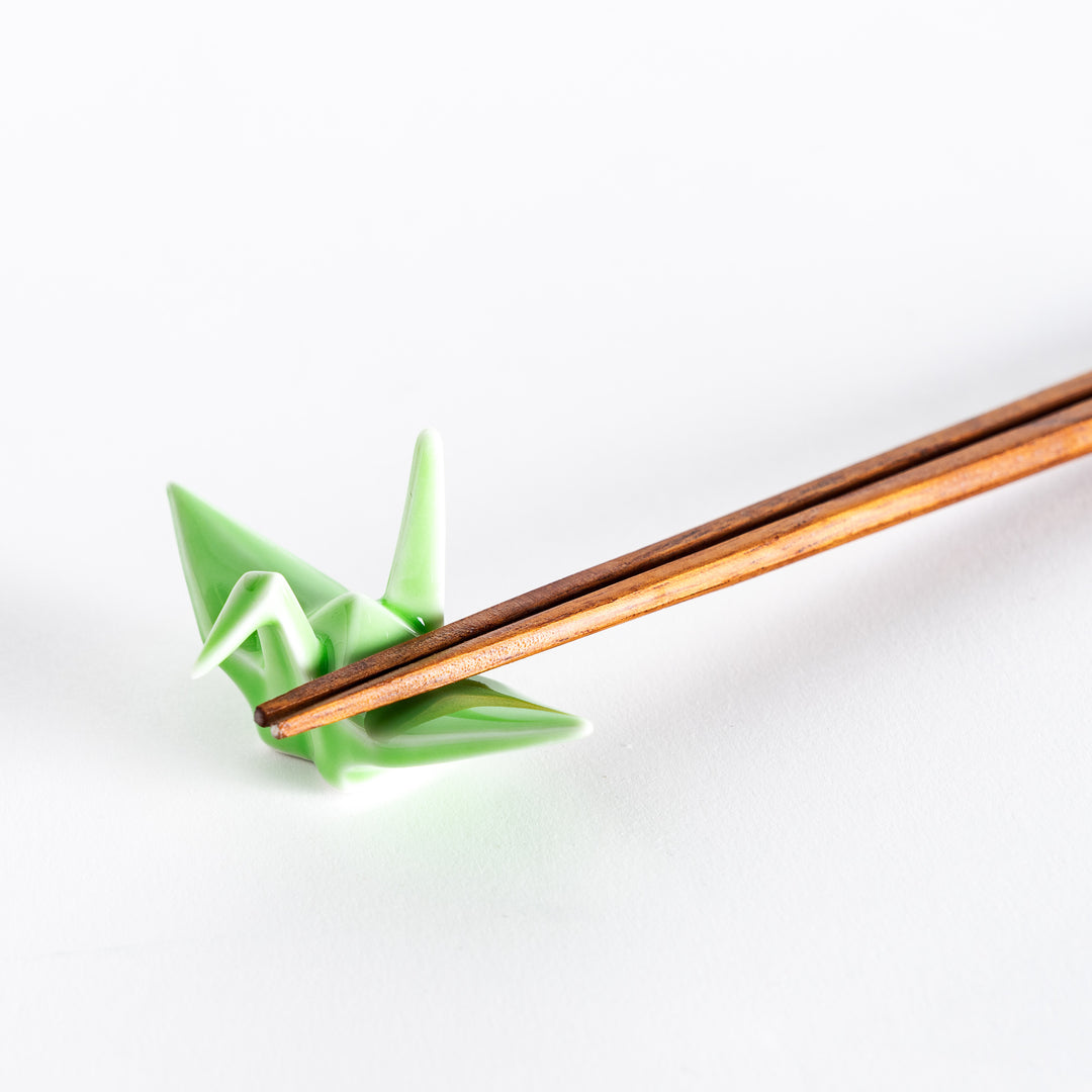 Close-up of chopsticks resting on the green ceramic crane-shaped chopstick rest.