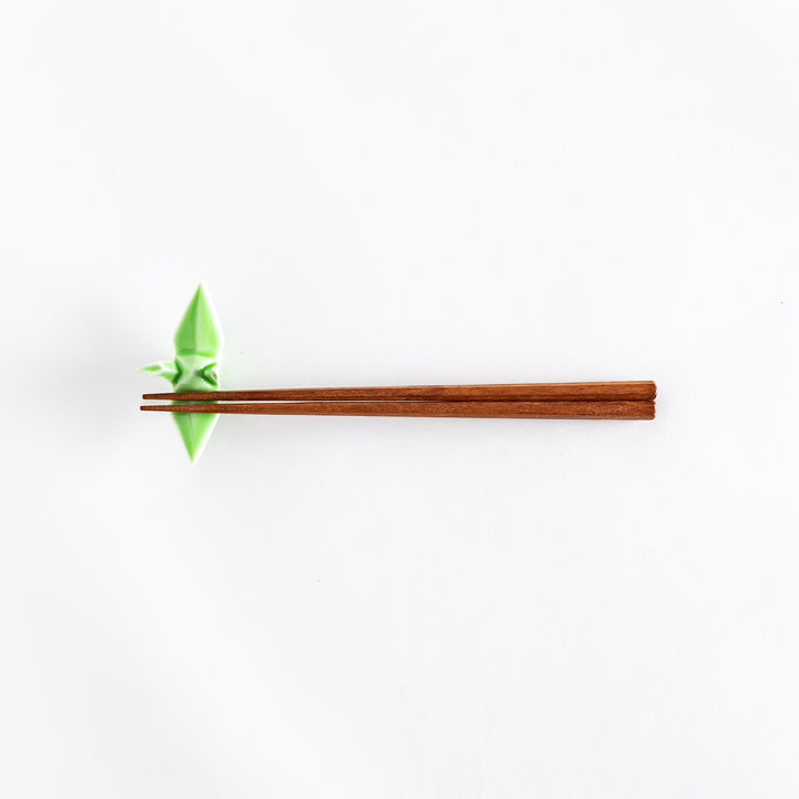 Wide view of chopsticks resting on the green ceramic crane-shaped chopstick rest.