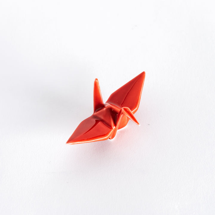 A red ceramic crane-shaped chopstick rest on a white background.