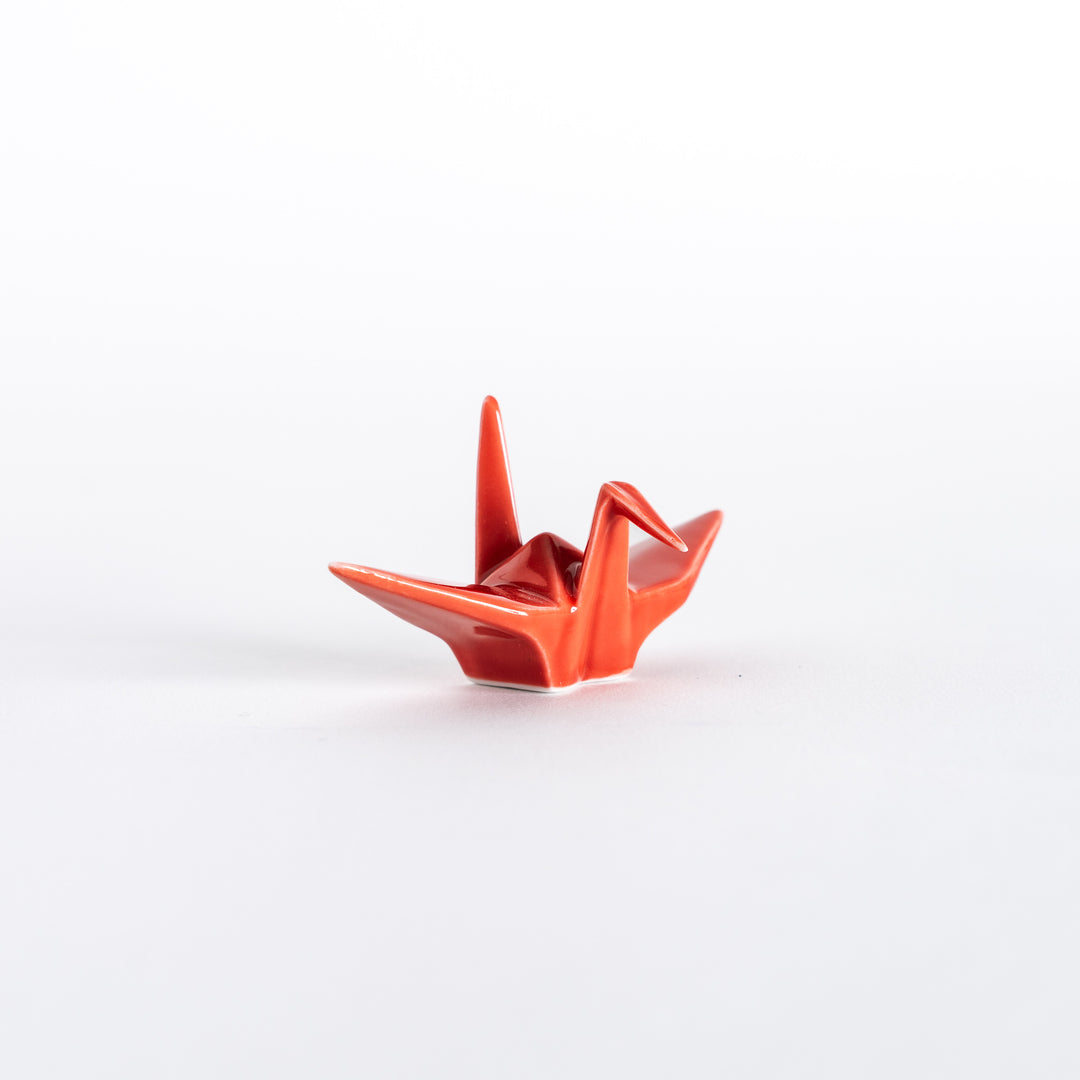 Front view of the red ceramic crane-shaped chopstick rest showing its detailed folds.