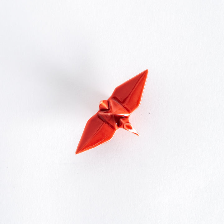 Top view of the red ceramic crane-shaped chopstick rest on a white surface.