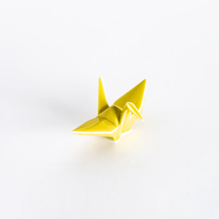 A yellow ceramic crane-shaped chopstick rest on a white background.