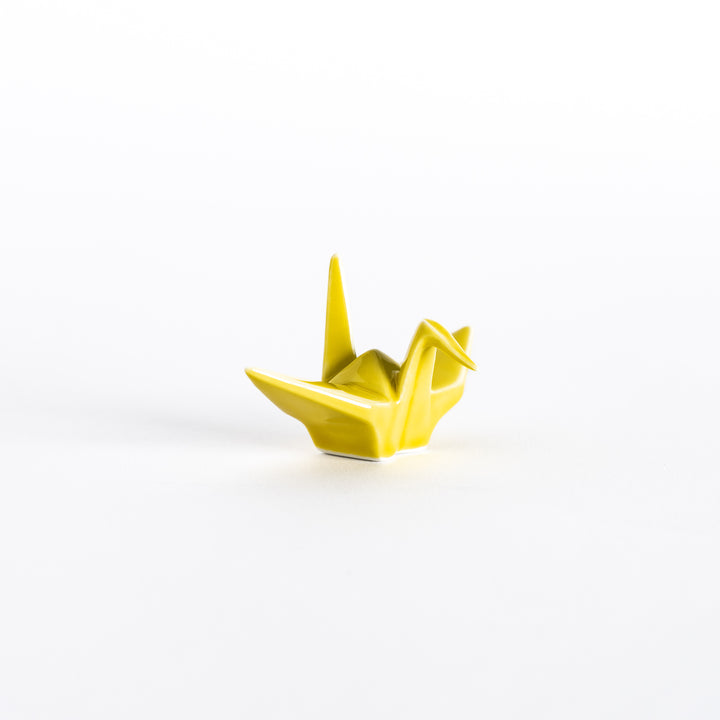 Front view of the yellow ceramic crane-shaped chopstick rest showing its delicate folds.