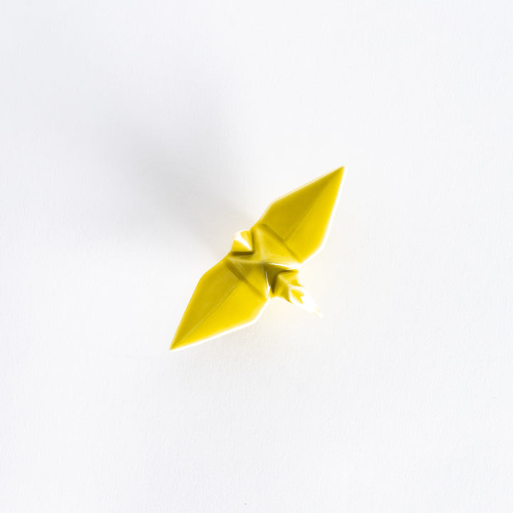 Top view of the yellow ceramic crane-shaped chopstick rest on a white surface.