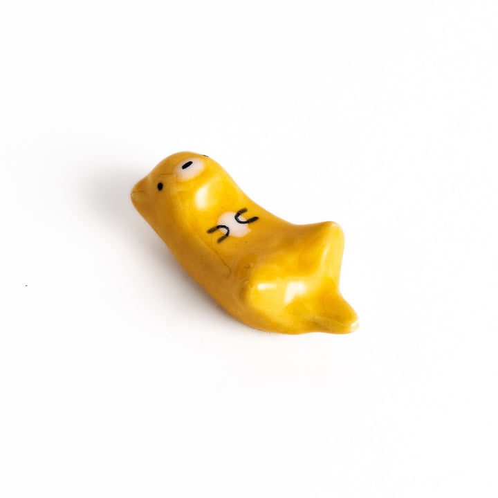 Otter Chopstick Rest featuring a cute otter design in glossy yellow, holding its belly, adding charm to your table setting.