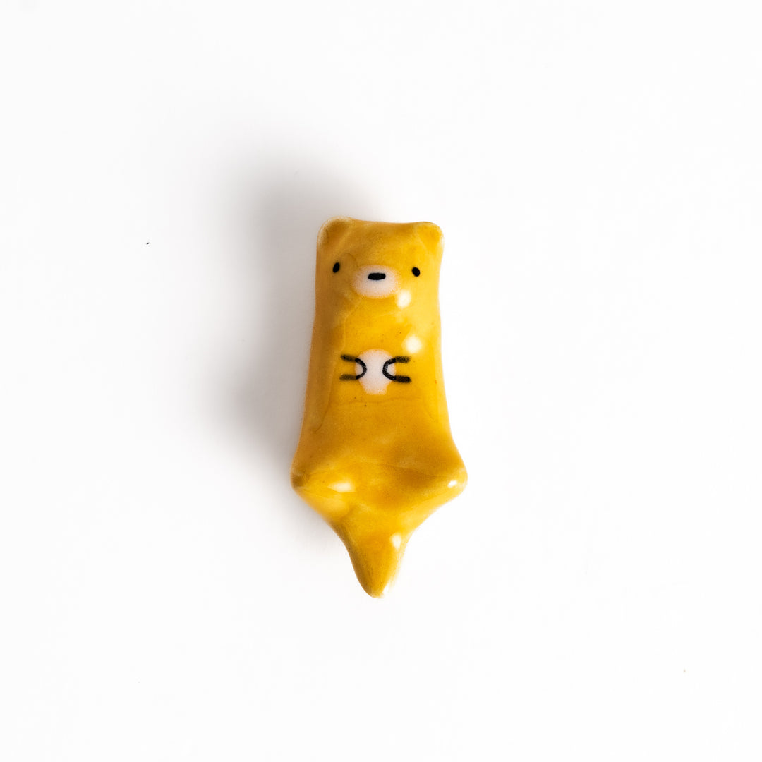 Otter Chopstick Rest featuring a cute otter design in glossy yellow, holding its belly, adding charm to your table setting.