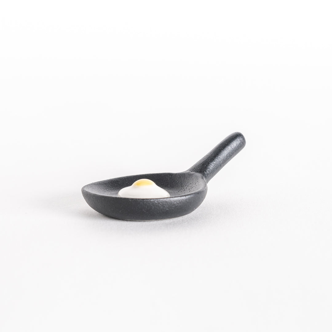 Side view of the frying pan chopsticks rest, highlighting the pan's shape and raised egg design.