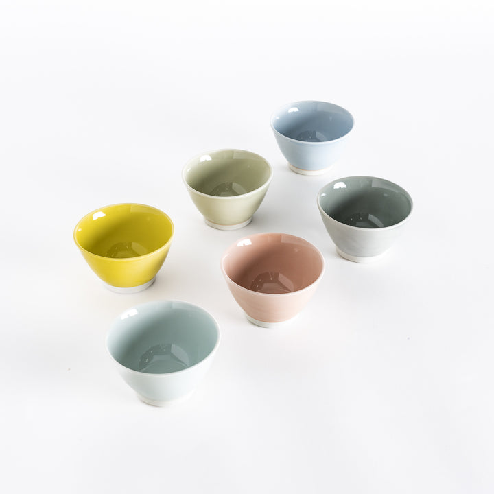 Six pastel dessert bowls in yellow, green, pink, blue, grey, and white, photographed at a slight angle, showcasing its elegant curves and soft pastel color.