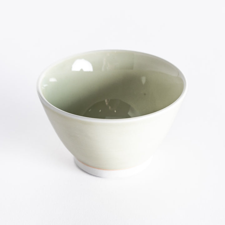 A light green dessert bowl, photographed at a slight angle, highlighting its elegant design and serene color.