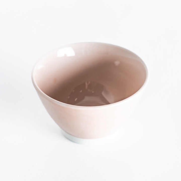 A soft pink dessert bowl, photographed at a slight angle, showcasing its pastel color and curved form.