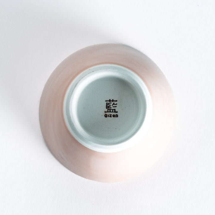 Bottom view of a soft pink dessert bowl, featuring its white base and minimalist design.