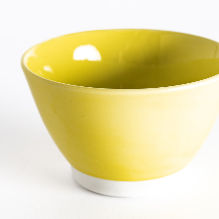 Close-up of a bright yellow dessert bowl, focusing on its glossy ceramic surface and vivid yellow hue.