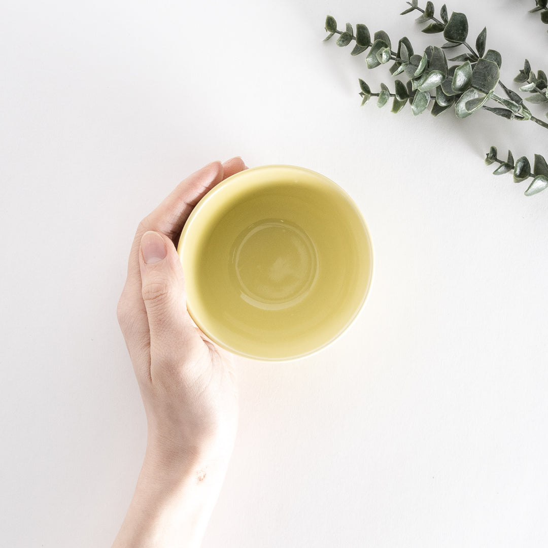 A bright yellow dessert bowl, photographed at a slight angle, showcasing its cheerful color and smooth design.