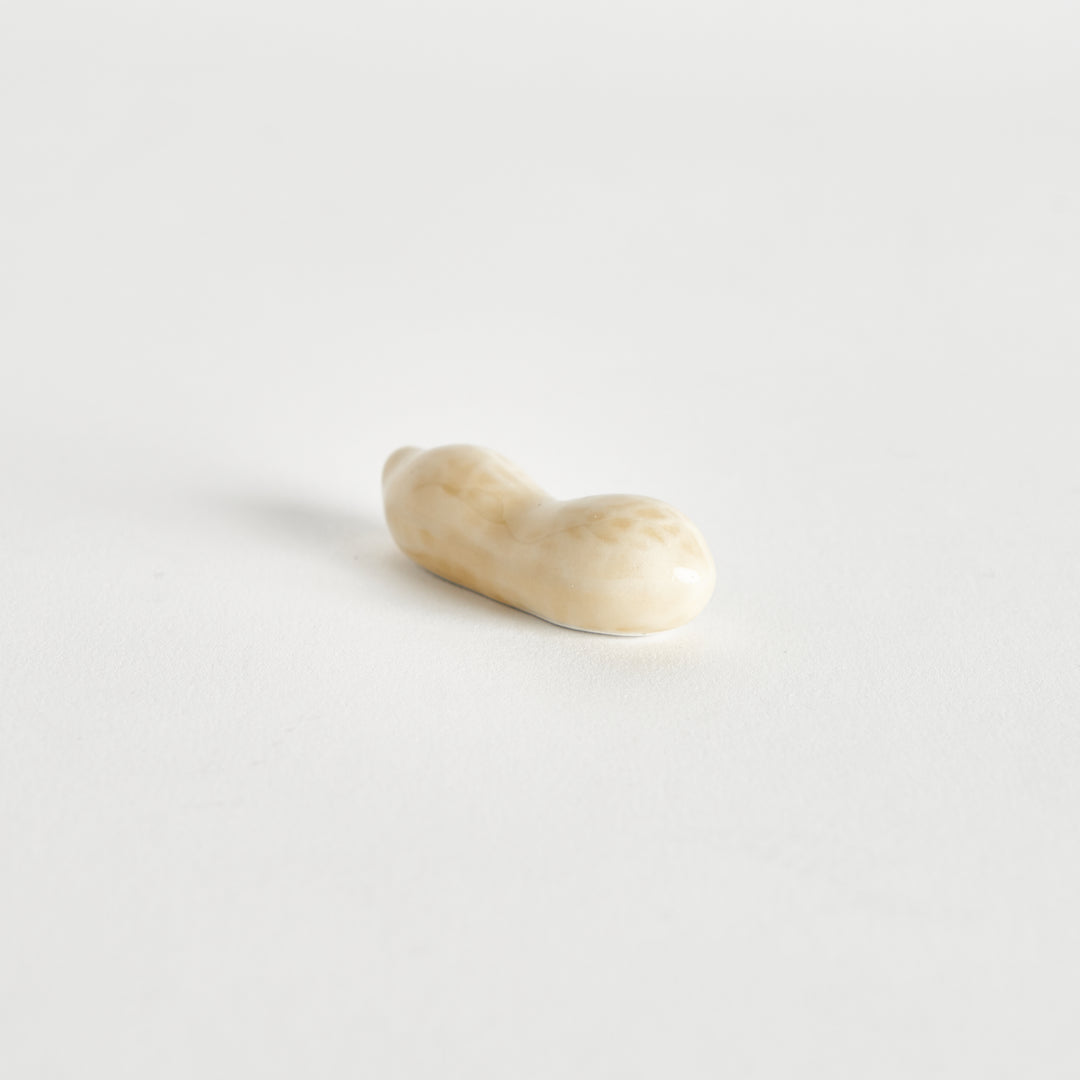 A light-colored peanut resting on its side on a clean white background.