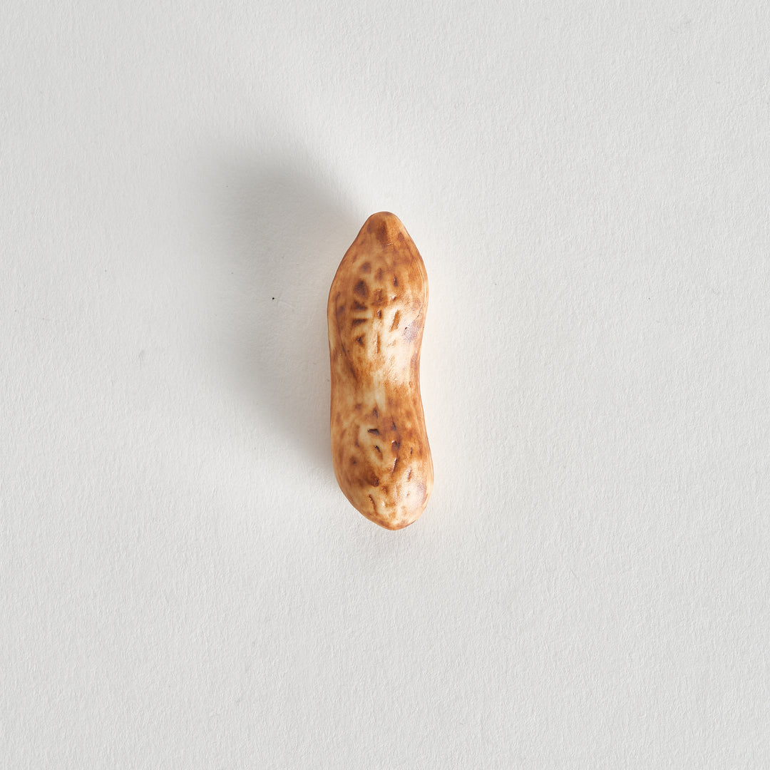 Close-up of a light brown peanut chopstick rest with intricate markings, placed horizontally with chopsticks.