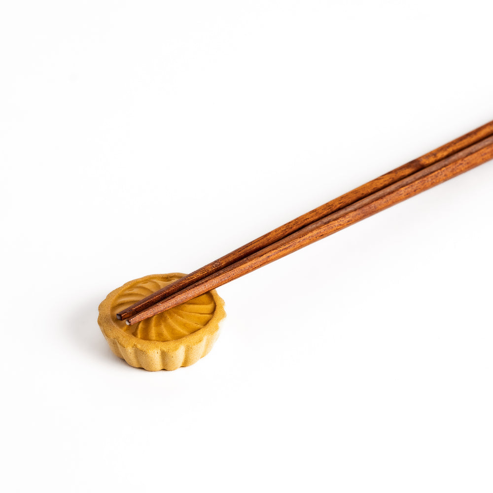 Pear Tart Chopstick Rest holding wooden chopsticks, showcasing its realistic tart design and functional, compact style.