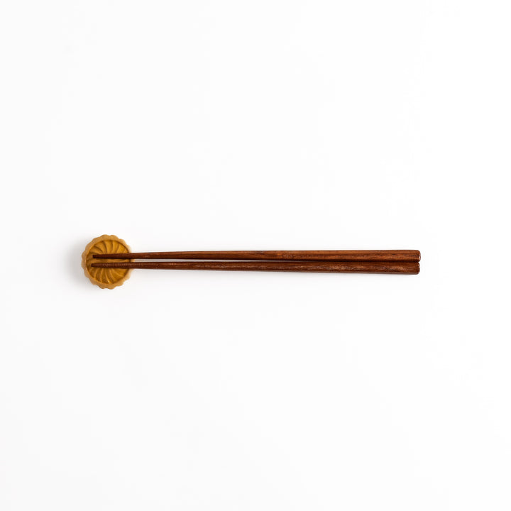 Pear Tart Chopstick Rest holding wooden chopsticks, showcasing its realistic tart design and functional, compact style.