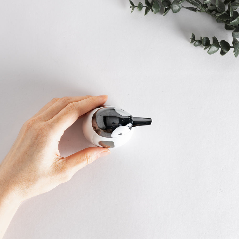 Hand holding the Penguin Soy Sauce Dispenser to show its compact size and rounded shape.