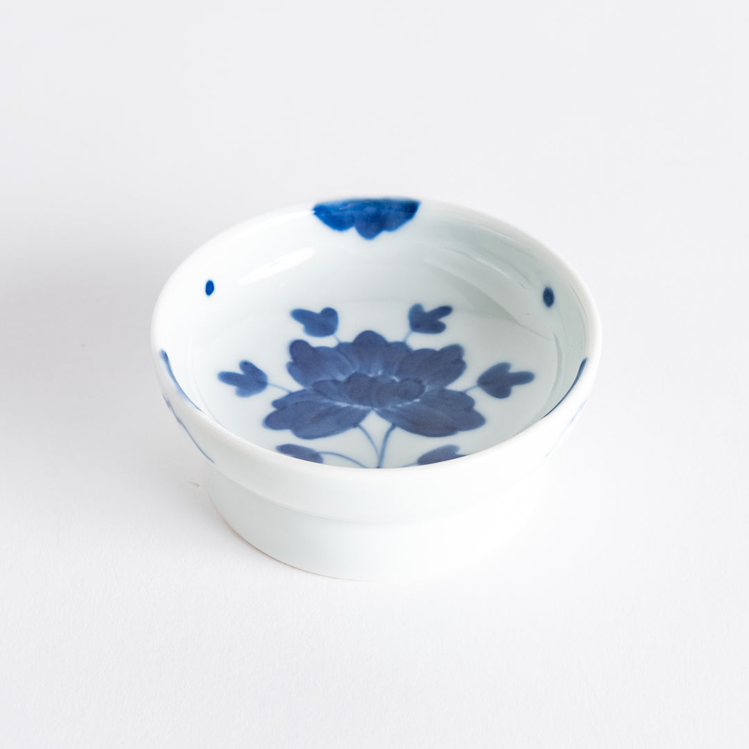 White raised sauce dish featuring a hand-painted blue peony flower.