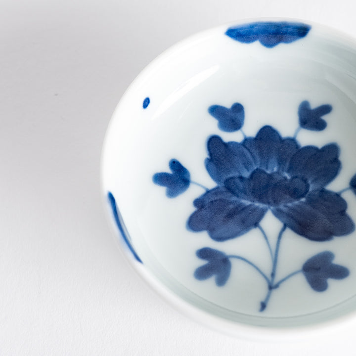 White raised sauce dish featuring a hand-painted blue peony flower.