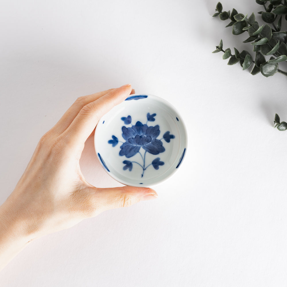 White raised sauce dish featuring a hand-painted blue peony flower.