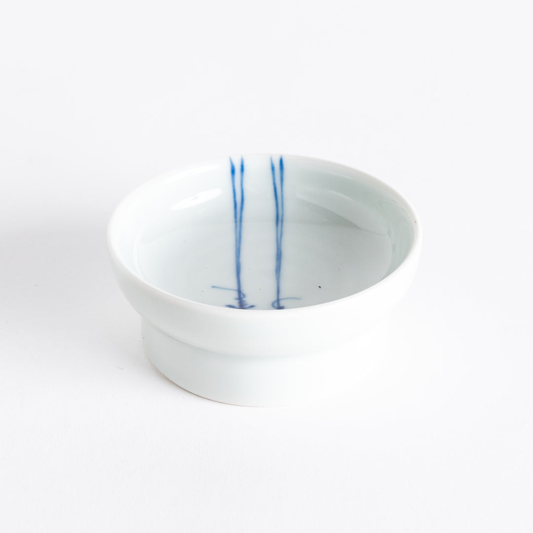 A small porcelain dish with a simple, elegant blue illustration of two persimmons.