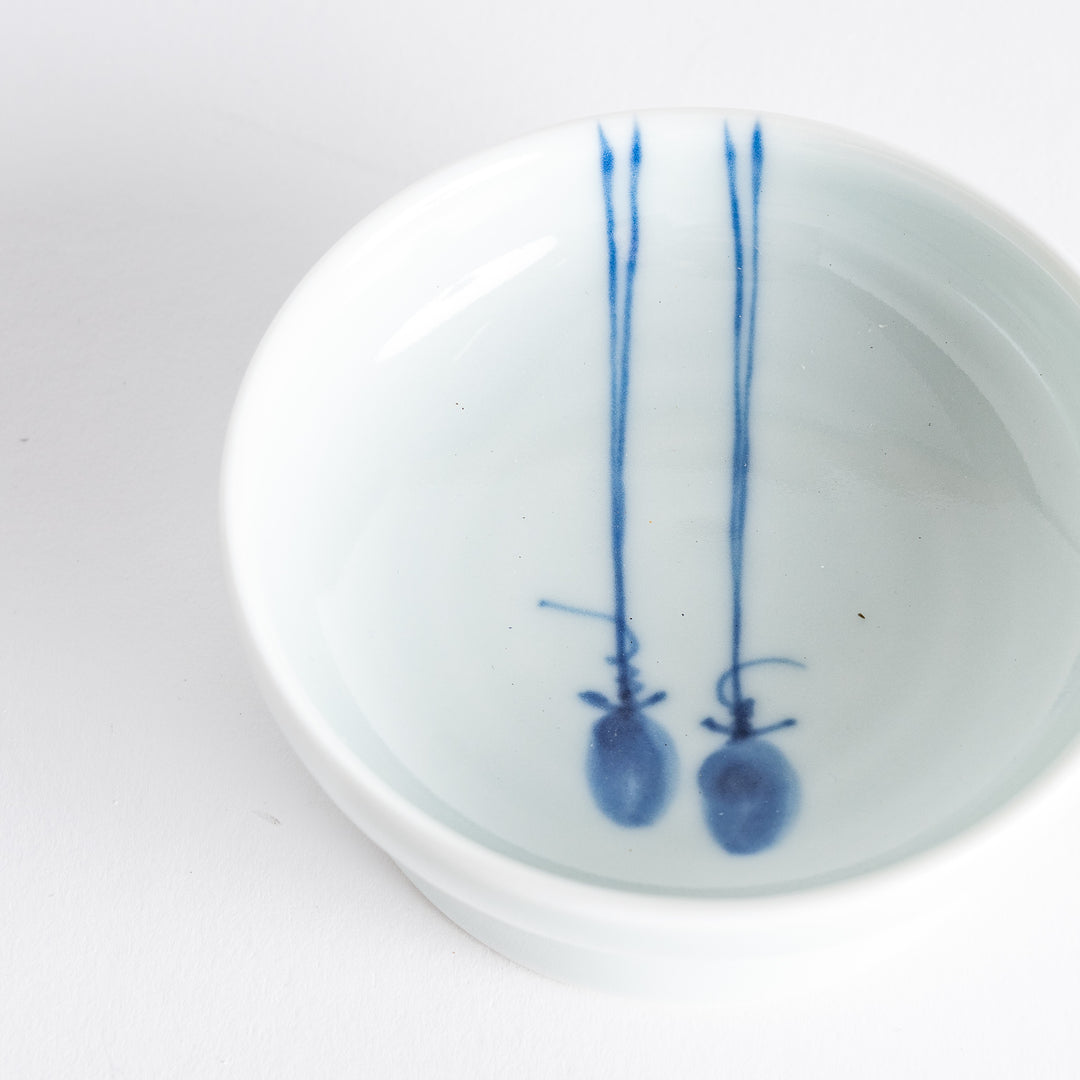 A small porcelain dish with a simple, elegant blue illustration of two persimmons.