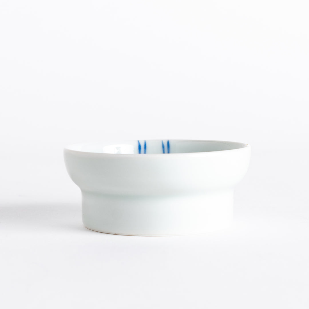 A small porcelain dish with a simple, elegant blue illustration of two persimmons.