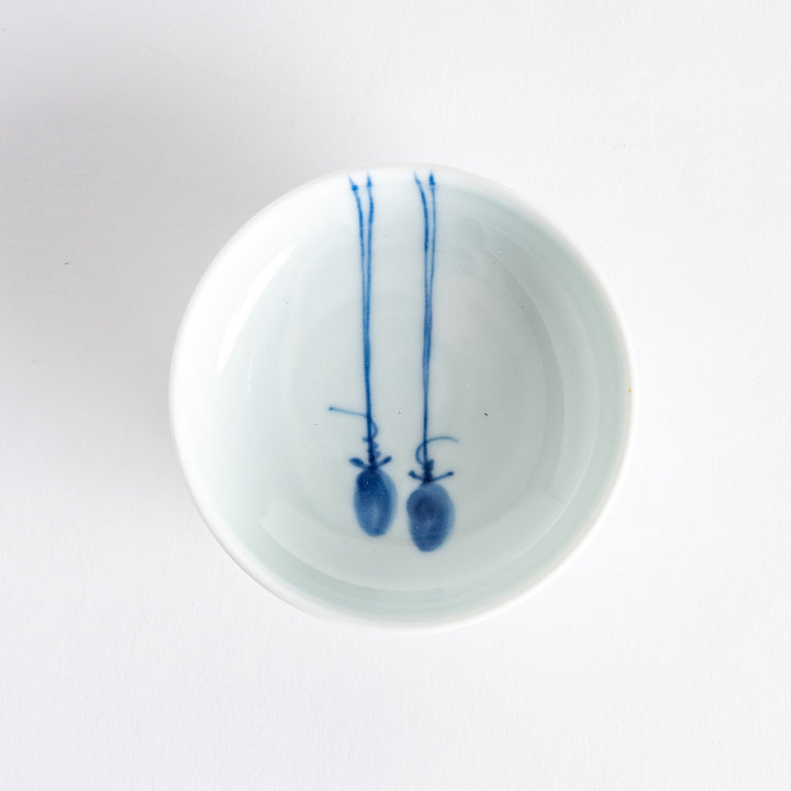 A small porcelain dish with a simple, elegant blue illustration of two persimmons.